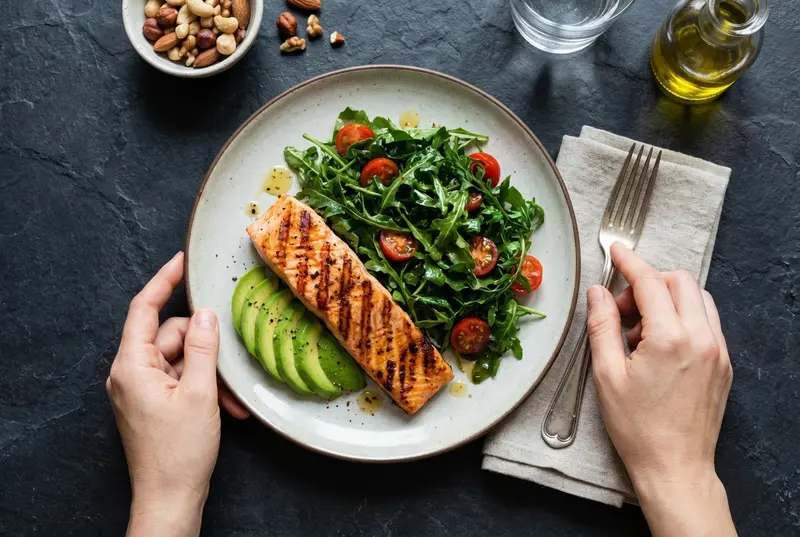 Finding Balance After a Diagnosis: A Guide to Metabolic Health and Resilience Overhead view of a healthy plate with salmon, avocado, and greens on a rustic table.